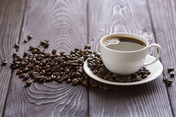 Cup of coffee on wooden background with coffee beans