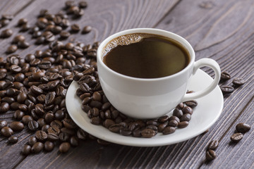 Cup of coffee on wooden background with coffee beans