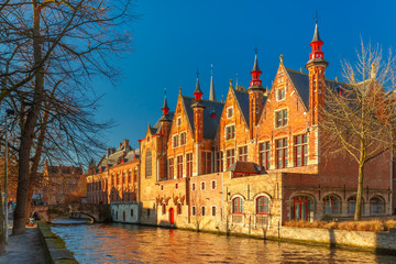 Scenic cityscape with a medieval tower Belfort and the Green canal, Groenerei, in Bruges in the morning, golden hour, Belgium