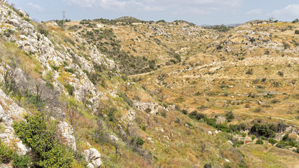 Fototapeta na wymiar Grass covered slope with huge rock boulders. Choirokoitia (Khirokitia) Neolithic Settlement. Cyprus.