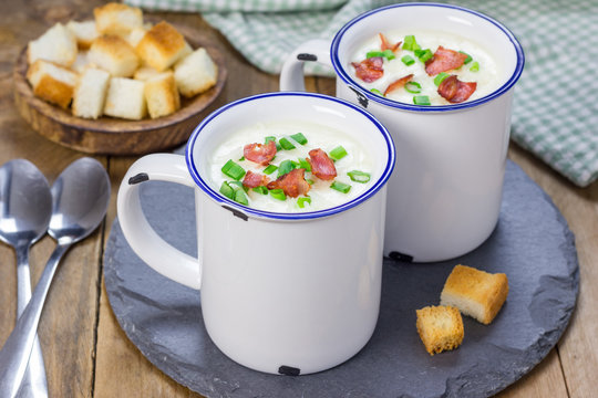 Creamy potato soup garnished with bacon and green onion, served in mug