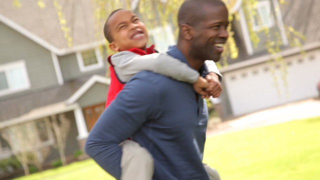 African American father and son play in front yard