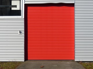 Rotes Rolltor in einer silbernen Wellblechfassade bei Sonnenschein am Segelflugplatz in Oerlinghausen bei Bielefeld am Hermannsweg im Teutoburger Wald in Ostwestfalen-Lippe © Martin Debus
