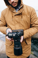 Unrecognizable man holding a camera near sea - cropped photo