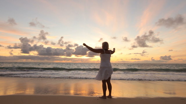 Woman standing on tropical beach at sunrise