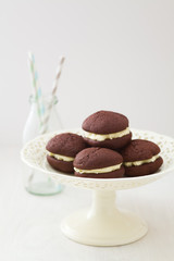 Chocolate whoopie pies with buttercream filling on cake stand