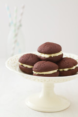 Chocolate whoopie pies with buttercream filling on cake stand