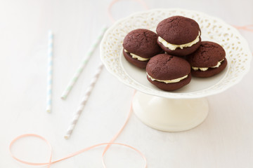 Chocolate whoopie pies with buttercream filling on cake stand