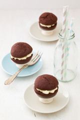 Three chocolate whoopie pies with buttercream filling on cake stand