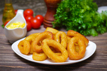 deep fried calamari with sauce and salad on a wooden background