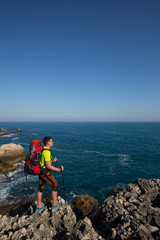 Hiker standing on top of the mountain with valley on the background.