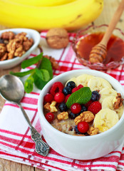 Healthy Breakfast. Oatmeal with fresh berries, bananas nuts and honey
