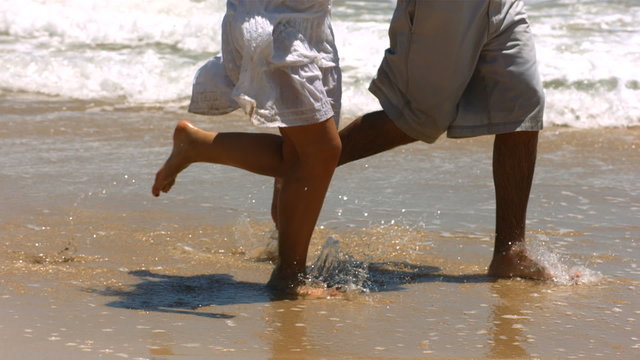 Closeup of couple's feet running in ocean surf