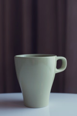 green teacup near window