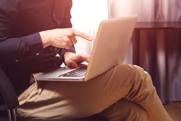 Freelance work. Casual dressed man sitting in chair inside his flat working on computer pointing with finger.
