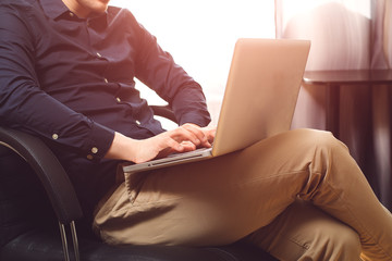 Freelance work. Closeup casual dressed man sitting in chair inside his flat working on computer...