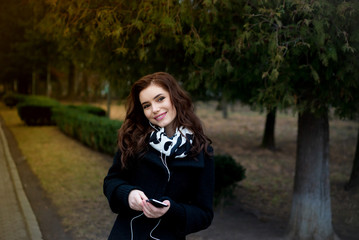 Beautiful girl listens to music in the park