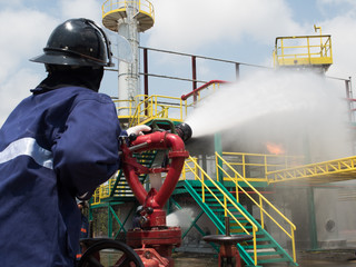 Firefighters fighting fire with pressured water during training exercise. Fire fighter spraying a straight steam into fire off.