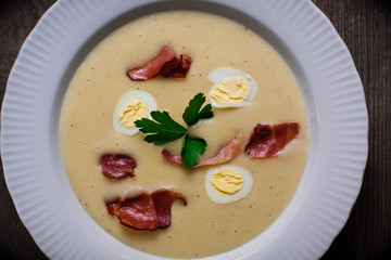 Horseradish cream soup with quail egg and black forest ham and a leaf of parsley.