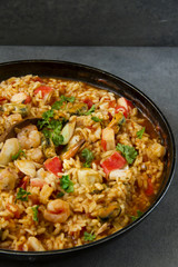 Spanish dish called paella with seafood, on the pan, grey background.
