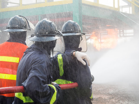 Firefighters fighting fire with pressured water during training exercise. Fire fighter spraying a straight steam into fire off.