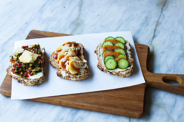 bruschettas with red fish and a cucumber, banana with peanut paste and almonds, tomato with a cucumber, bruschettas on a wooden board, tasty food 