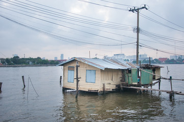 Fototapeta na wymiar Poor hut on riverside, taken from Bangkok Thailand