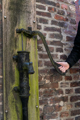 Mann betätigt eine alte Wasserpumpe mit der Hand