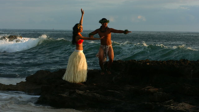 Polynesian dancers perform as waves crash on rocks