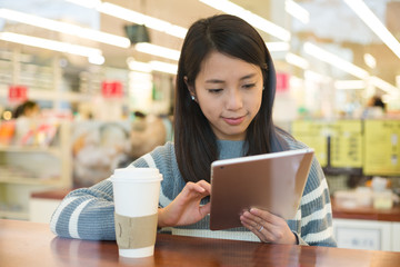 Asian young woman use of tablet pc with cup of coffee in cafe