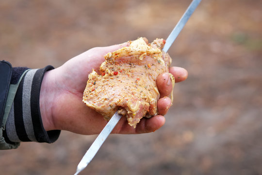 Man one hand holding the meat, other - stringing skewer. Stringi
