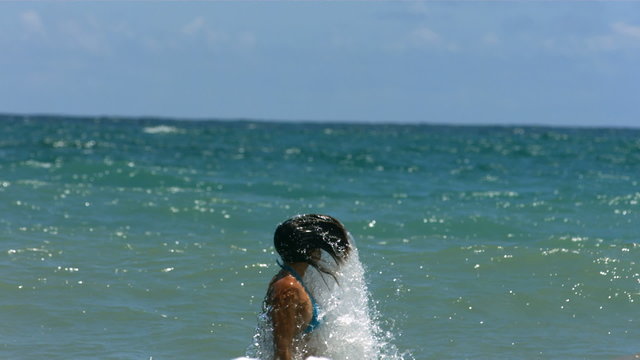 Woman splashes water in ocean, slow motion