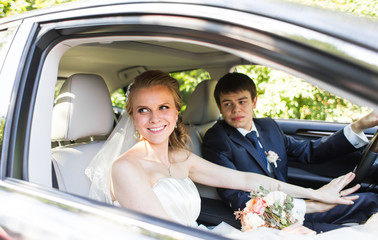 Bride and groom inside a  car. They are happy.