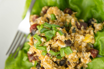 Scrambled eggs with sausage and spring onion on lettuce leaves