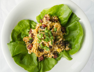 Scrambled eggs with sausage and spring onion on lettuce leaves
