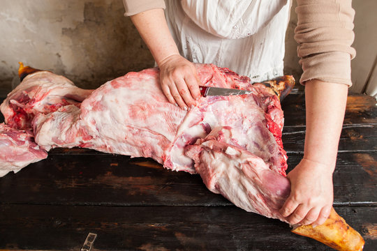 Butcher carving raw pork in local market 
