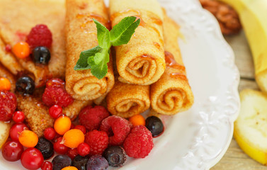Breakfast. Pancakes with honey and fresh berries - raspberries, cranberries, sea buckthorn and  cowberry. Selective focus
