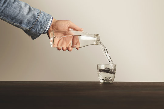 Hand pours clean water from bottle to cup