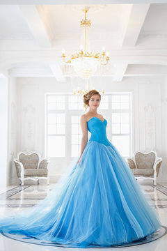 Beautiful bride in gorgeous blue dress Cinderella style in a morning in luxury interior