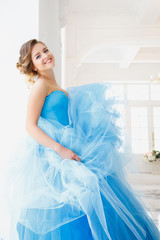 Beautiful bride in gorgeous blue dress Cinderella style in a morning in luxury interior