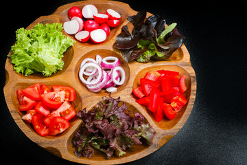 Wooden bowl with mixed ingredients for fresh vegetable salad