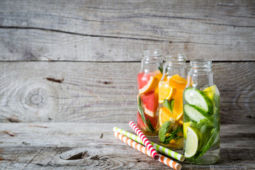 Selection of infused water in glass bottles, rustic wood background