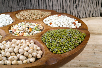 Wooden bowl of various legumes on wooden background copy space