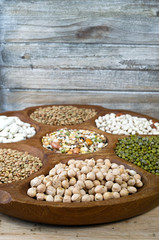 Fototapeta na wymiar Wooden bowl of various legumes on wooden background copy space