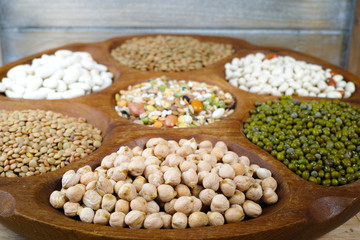 Wooden bowl of various legumes on wooden background copy space