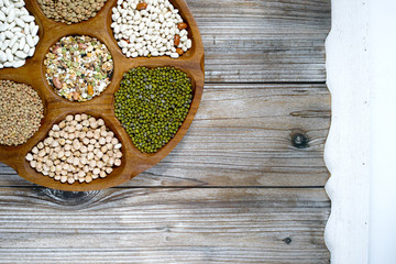 Wooden bowl of various legumes on wooden background copy space