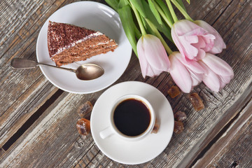 cup of coffee, cake, pink tulips on wooden background