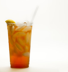 Fresh brewed Iced tea or sweet tea in a clear cup tie a straw and lemon wedge.