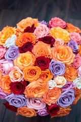 big round bouquet of colorful roses on a background dark wood