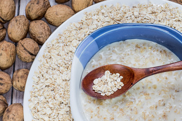 Porridge with a Wooden Spoon with Walnut on a Background